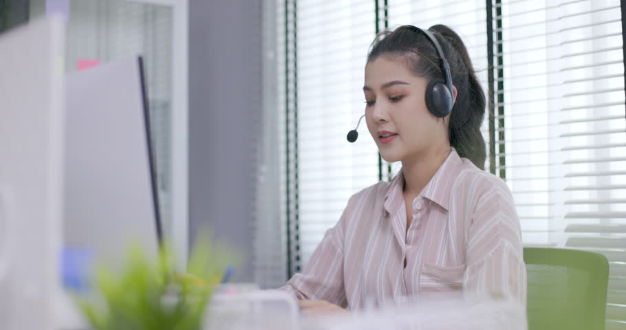 female call center worker is consulting with a customer who calls in for information over the phone in the office. Businessman wearing headphones to talk to customers. communication technology Royalty-Free Stock Footage #1106278535