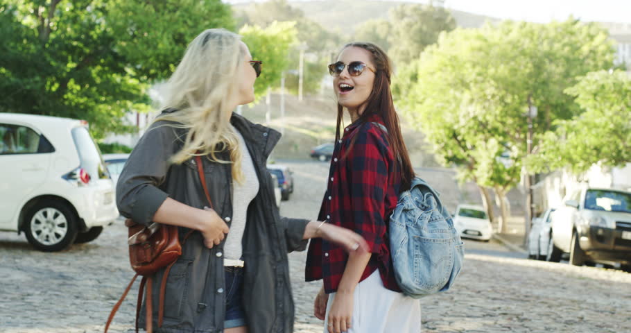 Girl friends, travel and pointing with happiness walking in a city road on vacation. Young people, sight seeing and female person with friend on holiday with freedom and adventure on urban street