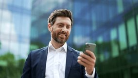 Handsome bearded Businessman using mobile Phone. Mature adult man texting Message, chatting on his Smartphone whileis standing in Office District. Business. Social Networking technology People. App - Powered by Shutterstock - Get 15% off with code: PIKWIZARD15