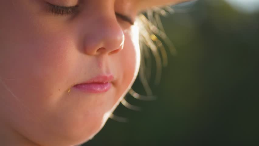 Child girl eats fast food potato chips with pleasure. Child eats in park in nature in summer. Girl smiling while eating chips, Fatty food for snack. Child nutrition. Unhealthy fast food
