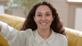 Social media content. Young happy curly woman recording video stories for social media, holding smartphone in outstretched hand, camera pov portrait