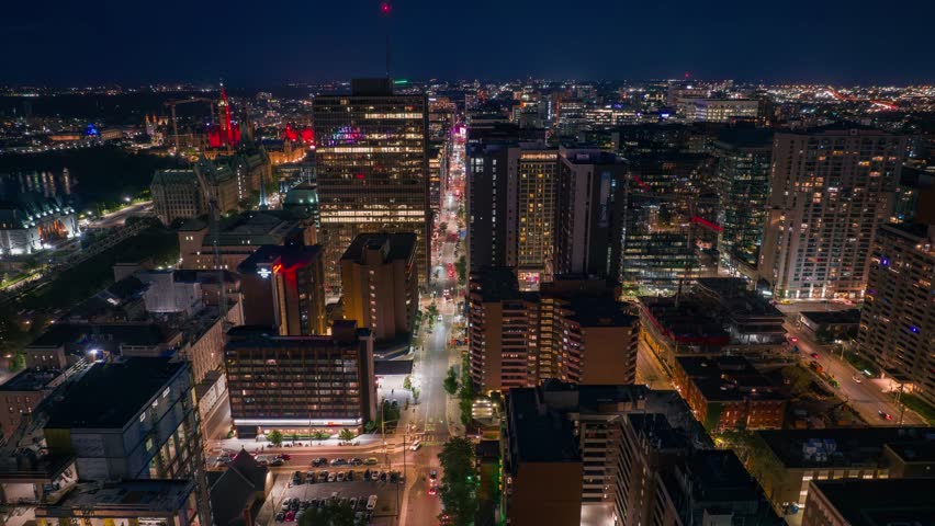 Aerial dolly left aerial timelapse of downtown Ottawa, Canada's capital at night. Traffic can be seen moving along city streets and there is a light show on the parliament buildings. Royalty-Free Stock Footage #1106291241