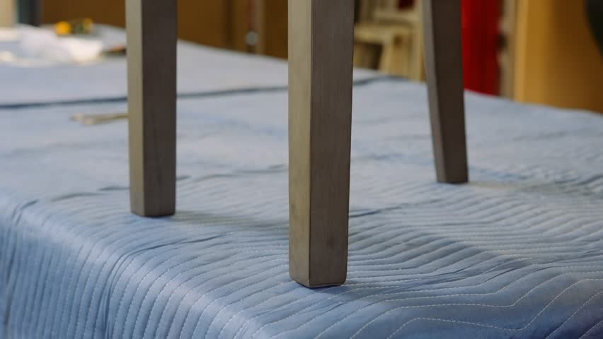 A furniture repair carpenter checks the wobbly legs on a wooden dining room chair on a workbench