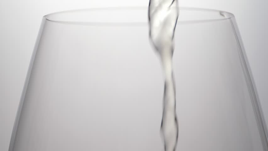 Pouring white wine into glass. Degustation of luxury beverage. Slow motion. Closeup