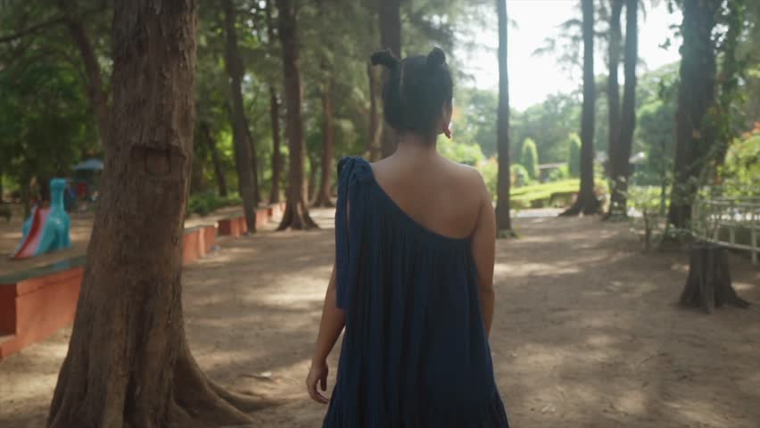 Girl walks through natural park garden. Woman hiking solo. Teenager lady hike trail, hazy sunny day. people in park in forest. Active lifestyle. People in woods Tourist walk in summer, cinematic