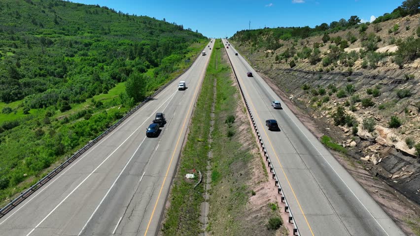 Aerial rising shot of scenic highway in Rocky Mountains in summer. Travelers visit national parks.