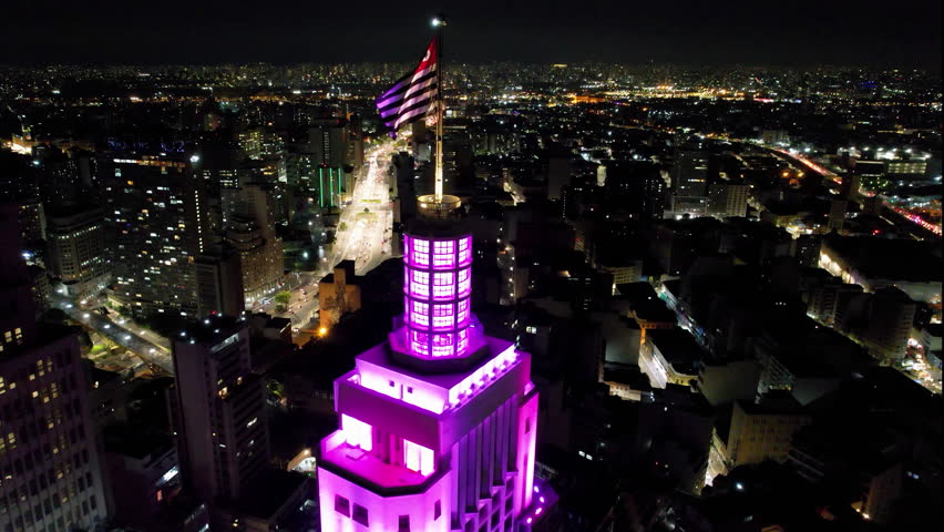 Flag waving at Santander Bank Brazil. Night cityscape of Sao Paulo Brazil. Downtown Sao Paulo. Night metropolis landscape of Sao Paulo Brazil. Highrise building of Santander Lighthouse Sao Paulo