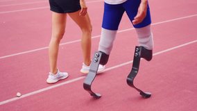 Close up of athlete with prosthetic blades and trainer walk in stadium.  Attractive amputee male runner and young sportswoman feel happy and enjoy practicing workout for Paralympic running competition - Powered by Shutterstock - Get 15% off with code: PIKWIZARD15