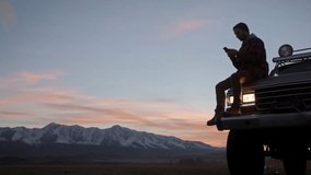 Male traveler is making route, while is sitting on a car hood against mountains view. Caucasian man, traveler and adventurer with a beard consulting his mobile phone leaning on his 4x4 car - Powered by Shutterstock - Get 15% off with code: PIKWIZARD15