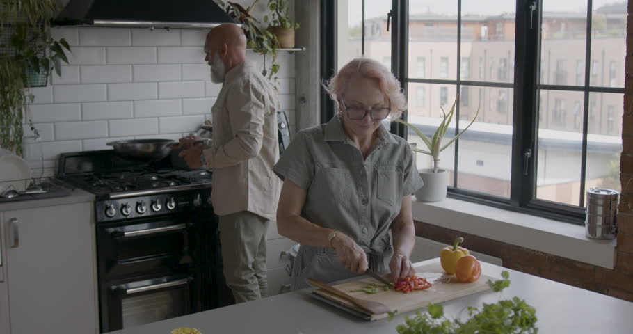 Senior Adult Couple at Home Cooking in Kitchen Together. Royalty-Free Stock Footage #1106309773