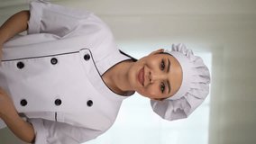 Vertical shots of portrait confident attractive woman chef in uniform with hat talking and smiling by mobile video call chat application or social media. Webcam view, vertical video concept.