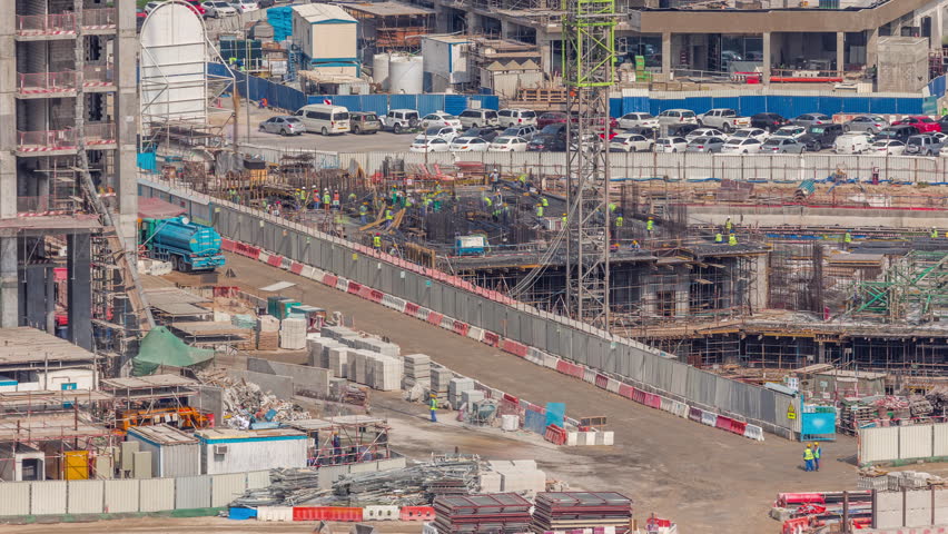 Large construction site with many working cranes timelapse. Workers creating reinforcement. Top aerial view of big development of residential and office district in Business bay, Dubai