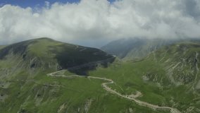 Beautiful roads of Romania. 4K aerial video with Transalpina road on top of the mountains with big clouds above. Curved waving road.