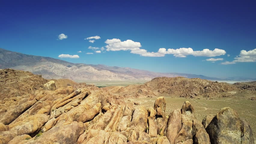 Aerial Shot Of Rocks Against Blue Sky During Sunny Day, Drone Flying Forward Over Landscape - Alabama Hills, California