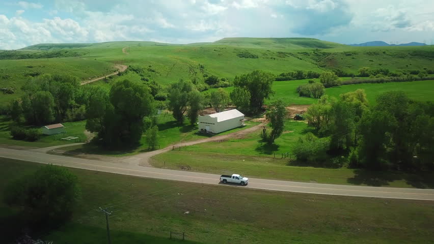 Aerial Shot Of Pickup Truck Moving On Country Road Passing Through Field, Drone Panning Over Landscape - Billings, Montana