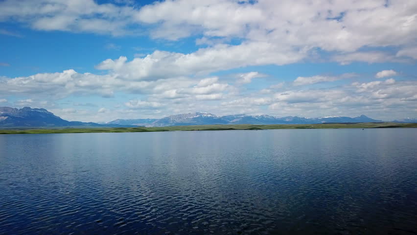 Aerial Shot Of Lake By Caravans Near Mountain Ranges, Drone Ascending Backward Over Natural Landscape Against Sky - Billings, Montana