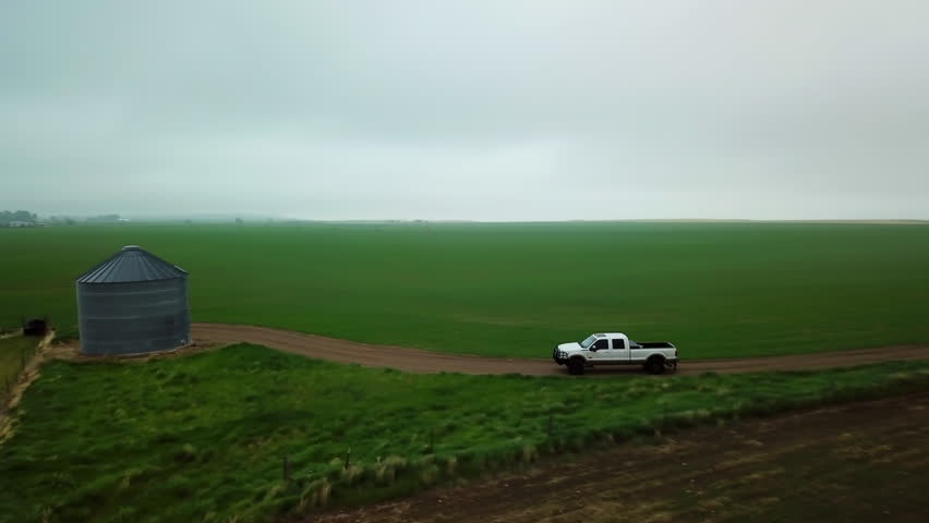 Panning Shot Of White Pickup Truck On Dirt Road By Silo Against Sky During Foggy Weather - Billings, Montana