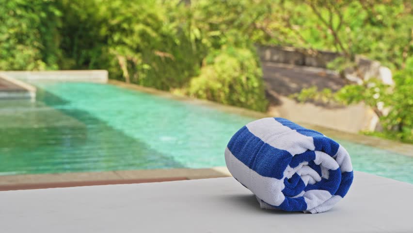 Pool towel sitting on sun lounger at luxury hotel room.
