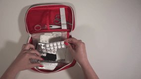 view from above. a woman opens a first aid kit. first aid kit and pills close-up. slow motion video. High-quality shooting in Full HD