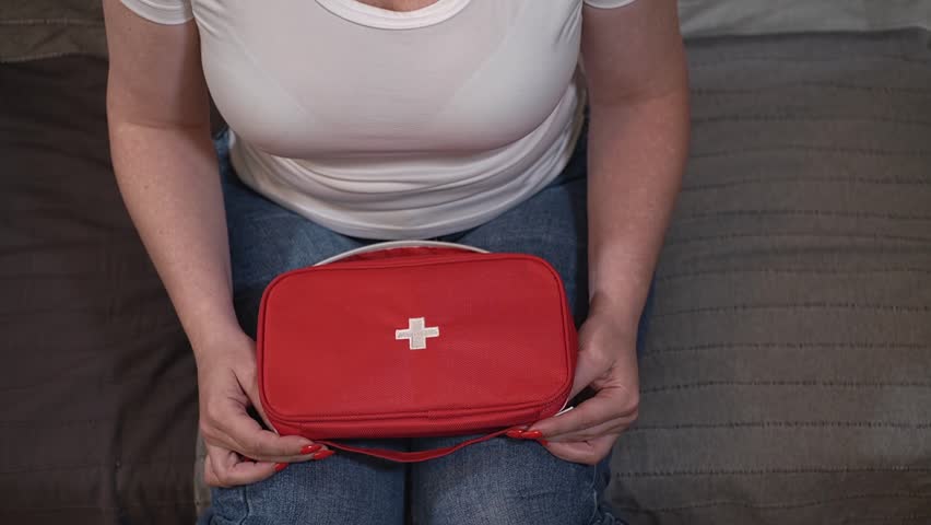 woman sitting on the bed looking for a pill in the first aid kit. first aid kit and pills. close-up. High-quality shooting in Full HD