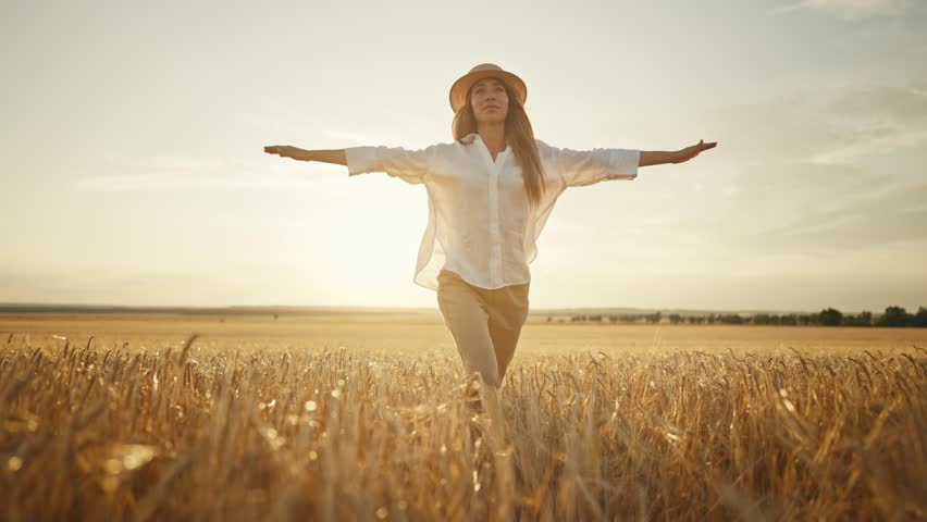 Romantic carefree happy woman running on yellow wheat field with spreading flying arms enjoying freedom calmness on rural nature during vacations holidays. Rest, relax in country, village at sunset. Royalty-Free Stock Footage #1106329111