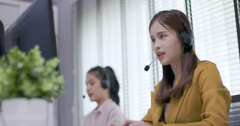 female call center worker is consulting with a customer who calls in for information over the phone in the office. Businessman wearing headphones to talk to customers. communication technology