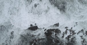video shot of sideways movement, aerial footage of waves breaking on a rocky shore