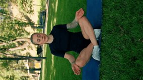 portrait of young sporty girl meditating doing yoga on sports mat outdoors while exercising park healthy lifestyle concept vertical video