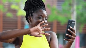 Happy young black woman makes a video call with her smartphone talking waving hello
