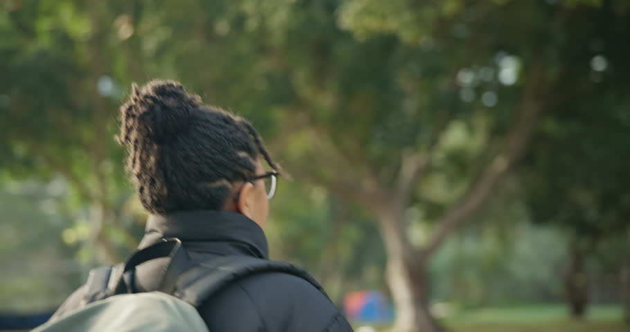 Travel, woman and walking in woods with backpack to relax in outdoor on vacation in side view. Girl, nature and hiker in forest for camping on holiday in environment with peace, freedom or sunshine.