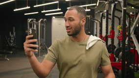 Tired exhausted African American man after sport workout exercise talking mobile phone video conference call trainer instructor sportsman athlete boxer with towel wipe sweat go walking through in gym - Powered by Shutterstock - Get 15% off with code: PIKWIZARD15