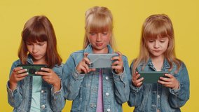 Worried funny teenage girls enthusiastically playing racing or shooter online video games on smartphone. Little children sisters using smartphone gadget app with drive simulator. Three siblings kids