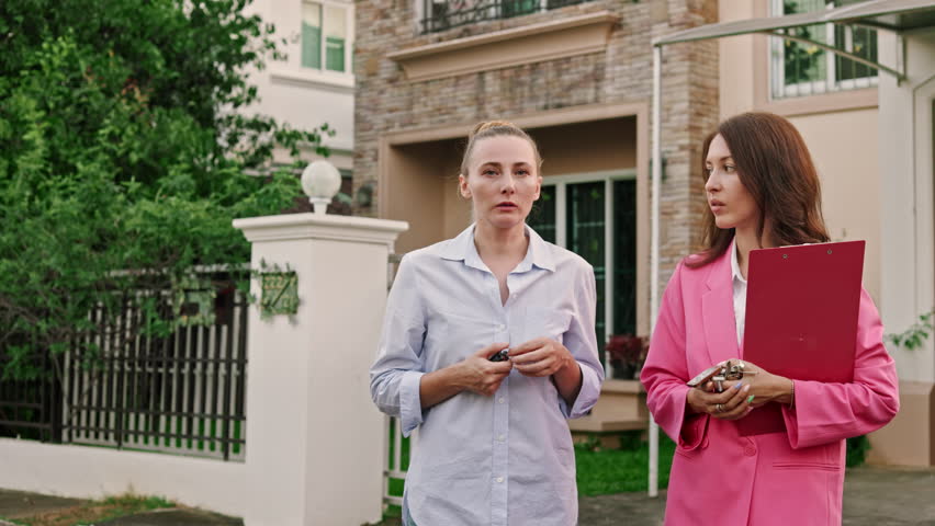 The realtor and her client exchanged thoughts and opinions as they surveyed the elegant houses in the exclusive village they were visiting. Royalty-Free Stock Footage #1106339965
