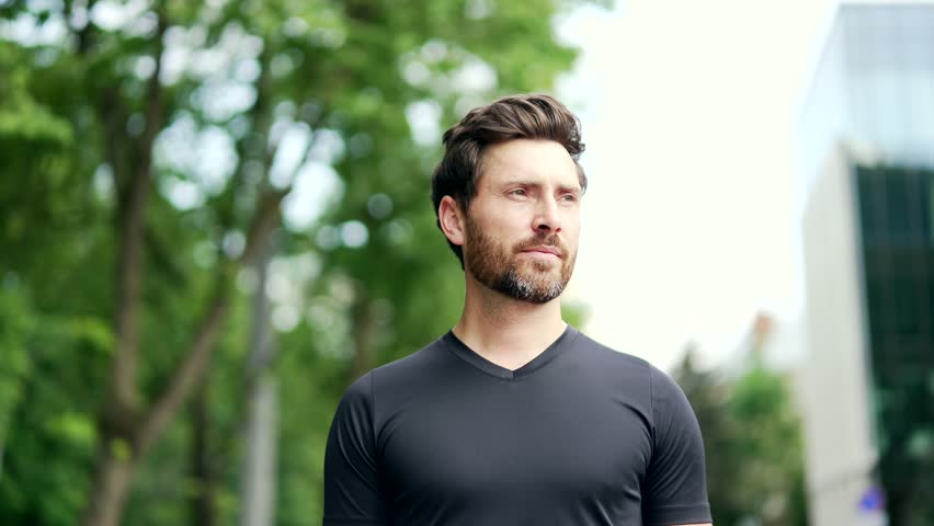 Portrait of happy bearded handsome sporty man in black t-shirt looking at camera. Mature adult sportsman runner on urban background outdoors outside healthy lifestyle morning workout on city street Royalty-Free Stock Footage #1106340549