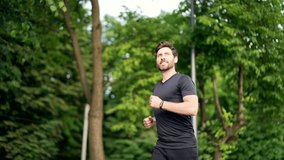 Handsome bearded male runner running on a urban park Sporty atlet man jogger jogging outdoors look at result a fitness tracker bracelet or smartwatch Active male enjoys morning activities in fresh air - Powered by Shutterstock - Get 15% off with code: PIKWIZARD15