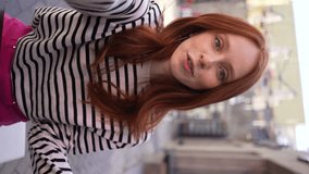 Vertical portrait of cheerful young woman talking video call looking at camera sitting at table in outdoor cafe terrace in sunny day. POV of happy redhead female having video chat using smartphone - Powered by Shutterstock - Get 15% off with code: PIKWIZARD15