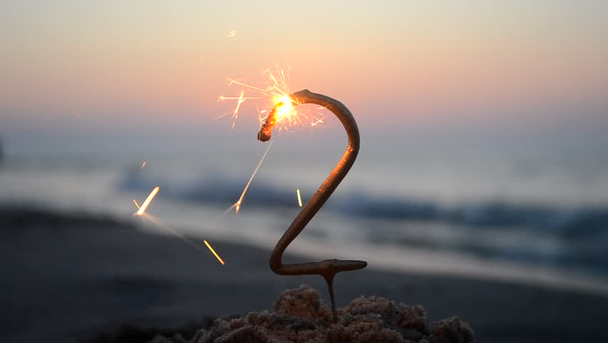 Bengal fire sparkler in the shape of the number two burning and sparkling on the sand on the beach of the sea coast during the dawn of the sunset. Concept holiday Birthday New Year party celebrating Royalty-Free Stock Footage #1106347311