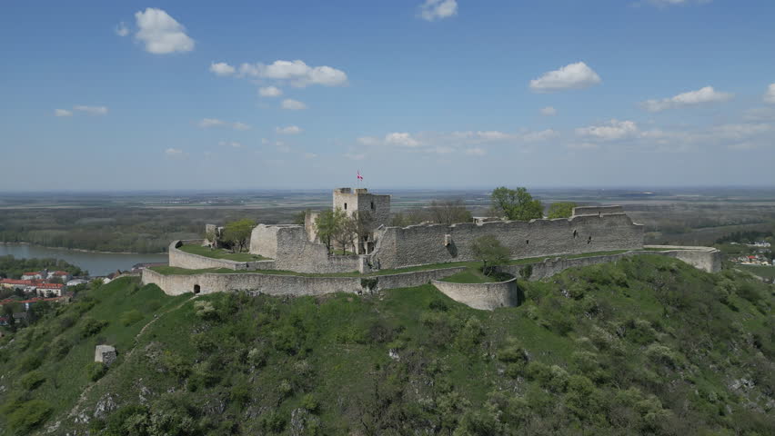 Aerial view of ruined castle on hill, city Hainburg an der Donau and Danube river in Austria, 4k