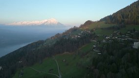 drone flies over the green mountain top. lake thunersee lies beneath the hill. snow-capped peaks on a backdrop. beauty of mesmerizing landscape in high-quality 4k filmed in interlaken, switzerland.