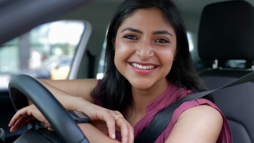Portrait of happy young native indian driver woman smiling at camera sitting inside a car parked in the city. Transportation and commuter people concept. Royalty-Free Stock Footage #1106356625
