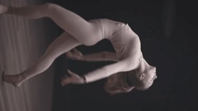 Young woman dance in a studio room, flexible female performs a stretching dance with yoga elements, vertical video for social networks.