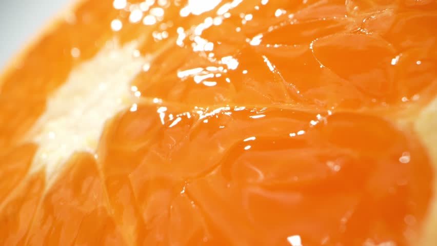 In a mesmerizing macro video, orange slices are expertly cut in half, revealing intricate patterns, vibrant hues, and glistening juice droplets. Fruit concept. Orange background
