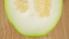 Macro video showcases the intricate details of a half Wax gourd, revealing its luscious flesh, delicate seeds, and textured rind. The probe lens captures the mesmerizing beauty within the fruit

