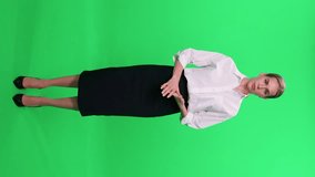 Woman blogger in suit looks into the camera and speaks on a green background, template for TV news agencies, journalist at work, vertical video, breaking news.