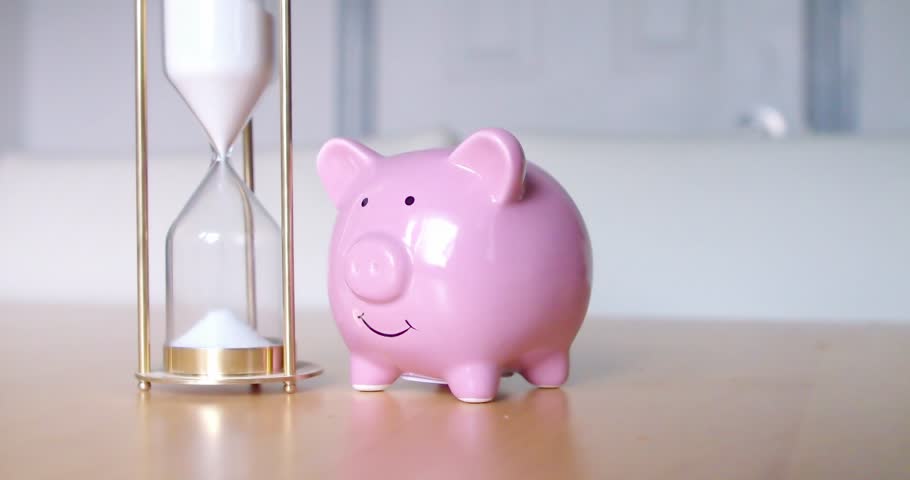 A dolly of a hourglass and a piggybank. Concept: growing saving takes time. Royalty-Free Stock Footage #1106359951
