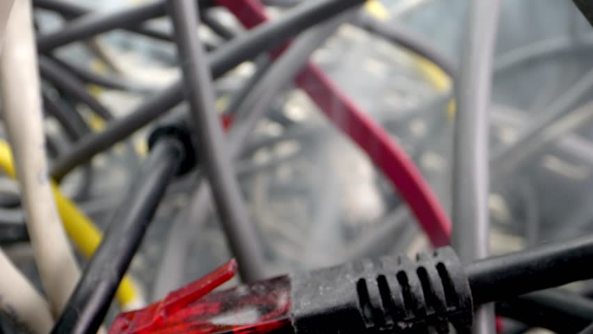 The camera lens cuts through the labyrinth of network cables and other obstacles. Disassembled wires, computer problems, and the sight of smoke suggesting a possible short circuit or fire outbreak. Royalty-Free Stock Footage #1106364689