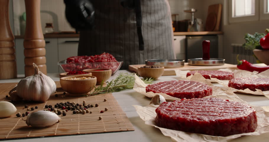 Chef prepares blanks for hamburgers from fresh minced meat in a kitchen with subdued lighting, Professional promotional video Advertising. Fresh minced meat, semi-finished products, blanks.  Royalty-Free Stock Footage #1106369315
