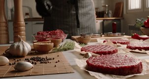 Chef prepares blanks for hamburgers from fresh minced meat in a kitchen with subdued lighting, Professional promotional video Advertising. Fresh minced meat, semi-finished products, blanks. 