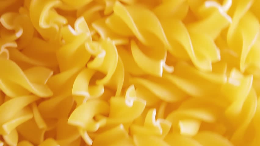 Uncooked Fusilli Pasta - Top View. Fat and Unhealthy Food. Dry Spiral Macaroni, Moving Background. Italian Culture and Cuisine. Raw Golden Pasta Pattern. Upward Movement