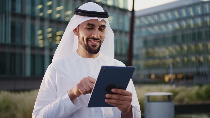 Handsome businessman with the traditional emirates white outfit working outdoor in Dubai city. Concept about middle eastern cultures and business Royalty-Free Stock Footage #1106372437